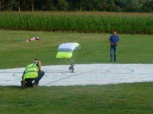 Fallschirmspringer landet auf der Zielplane Pilot im Hintergrund und Schiedsrichter im Vordergrund